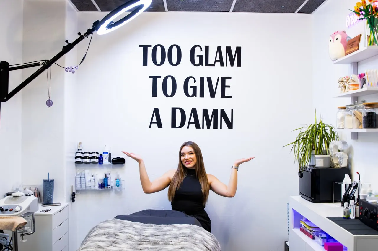 Gabriela, owner of GLAMSTHETICS SLC, in her Sugarhouse studio under the Too Glam to Give a Damn wall